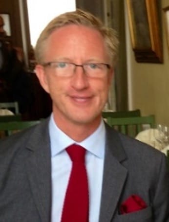Lars Kinnunen porträttbild. Lars är iklädd kostym och glasögon, han har ljust kort hår